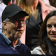 Bill Gates makes a face in a baseball cap while sitting in a crowd with his wife Melinda French Gates.
